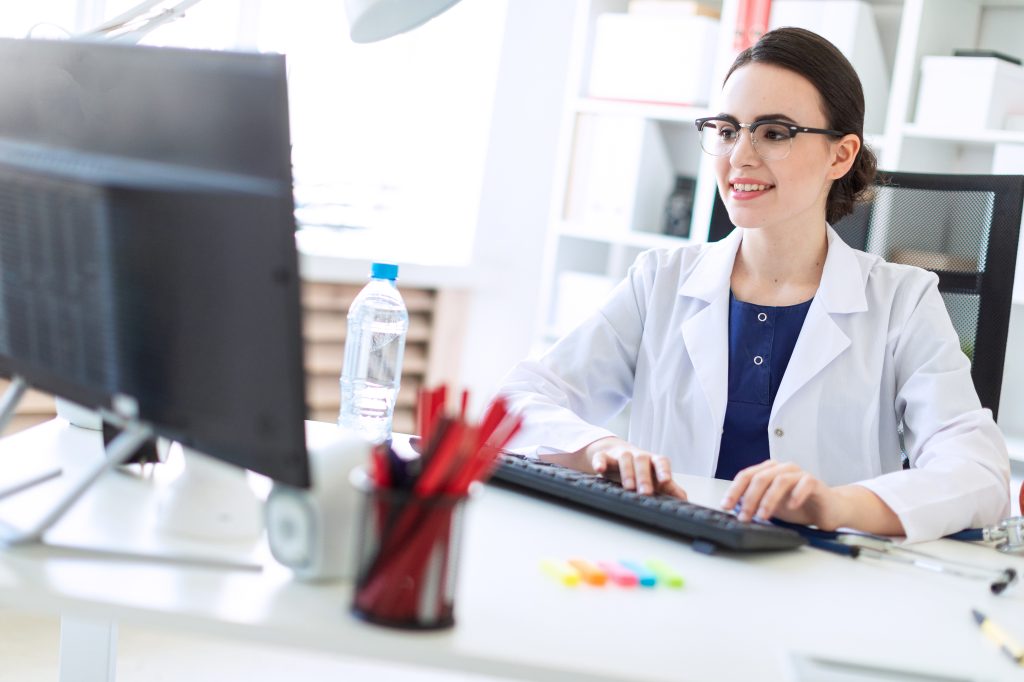 Doctor smiling while working at a computer. She is typing on a keyboard.